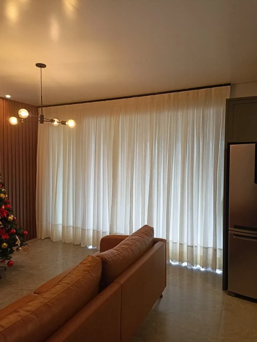 Projeto real de sala com cortina clara do piso ao teto e sofá em couro